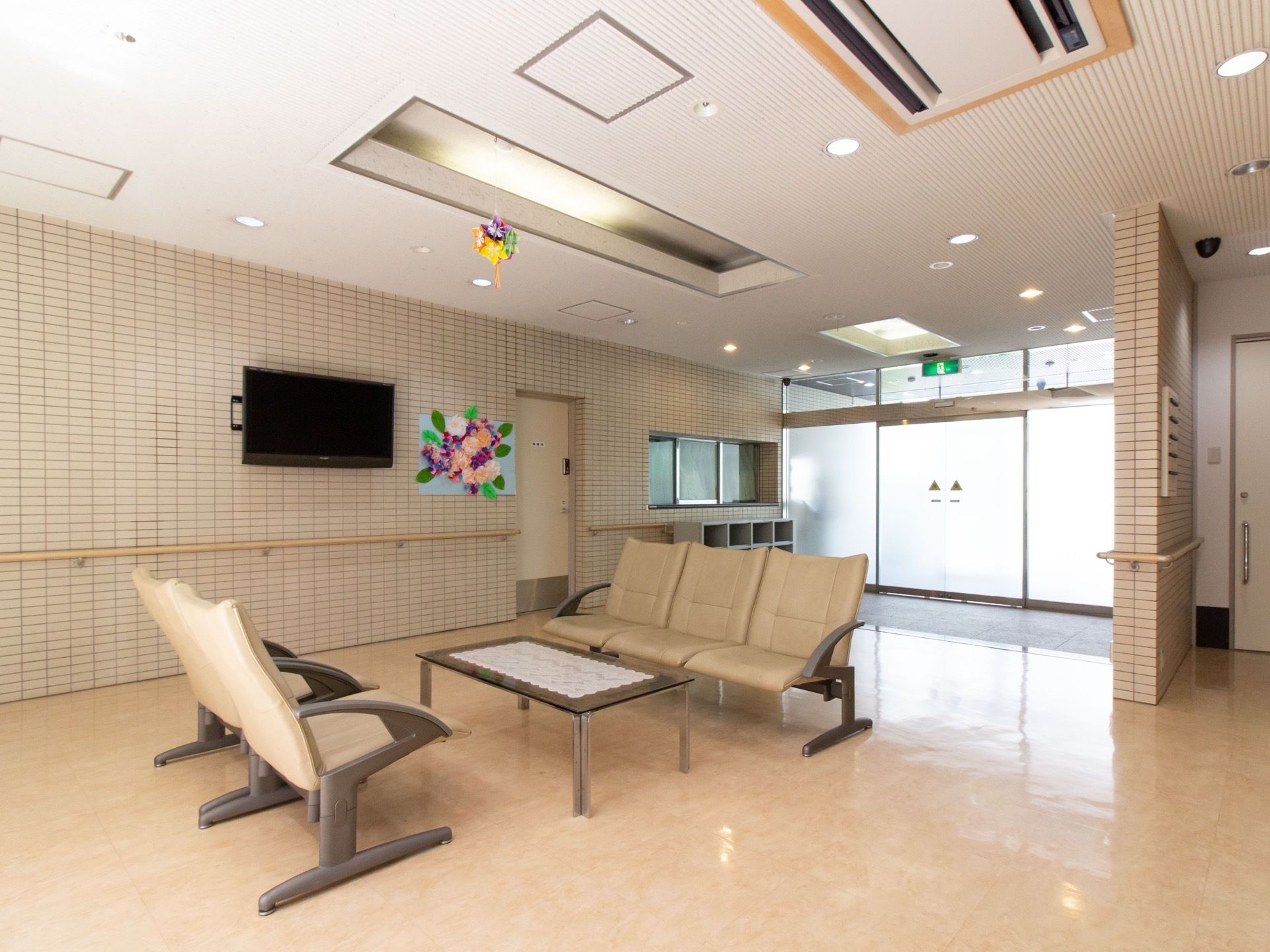 玄関入ってすぐのところに、５人分の椅子とテーブルが置かれている。壁には大型のテレビが掛けられている。