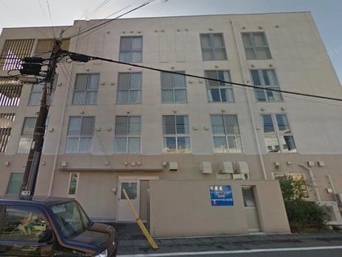 「百楽苑」の外観。4階建てのマンション施設であり、周辺に飲食店や商業施設がある。
