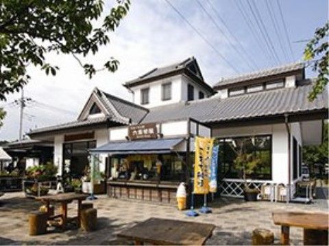 道の駅の外観である。建物は瓦屋根で白壁になっており、建物の前の広場には木製のテーブル、椅子が設置されている。