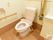 洋式のトイレが完備されている。可動式の手すりもある。壁側にはナースコール、トイレットペーパーホルダーが設置されている。