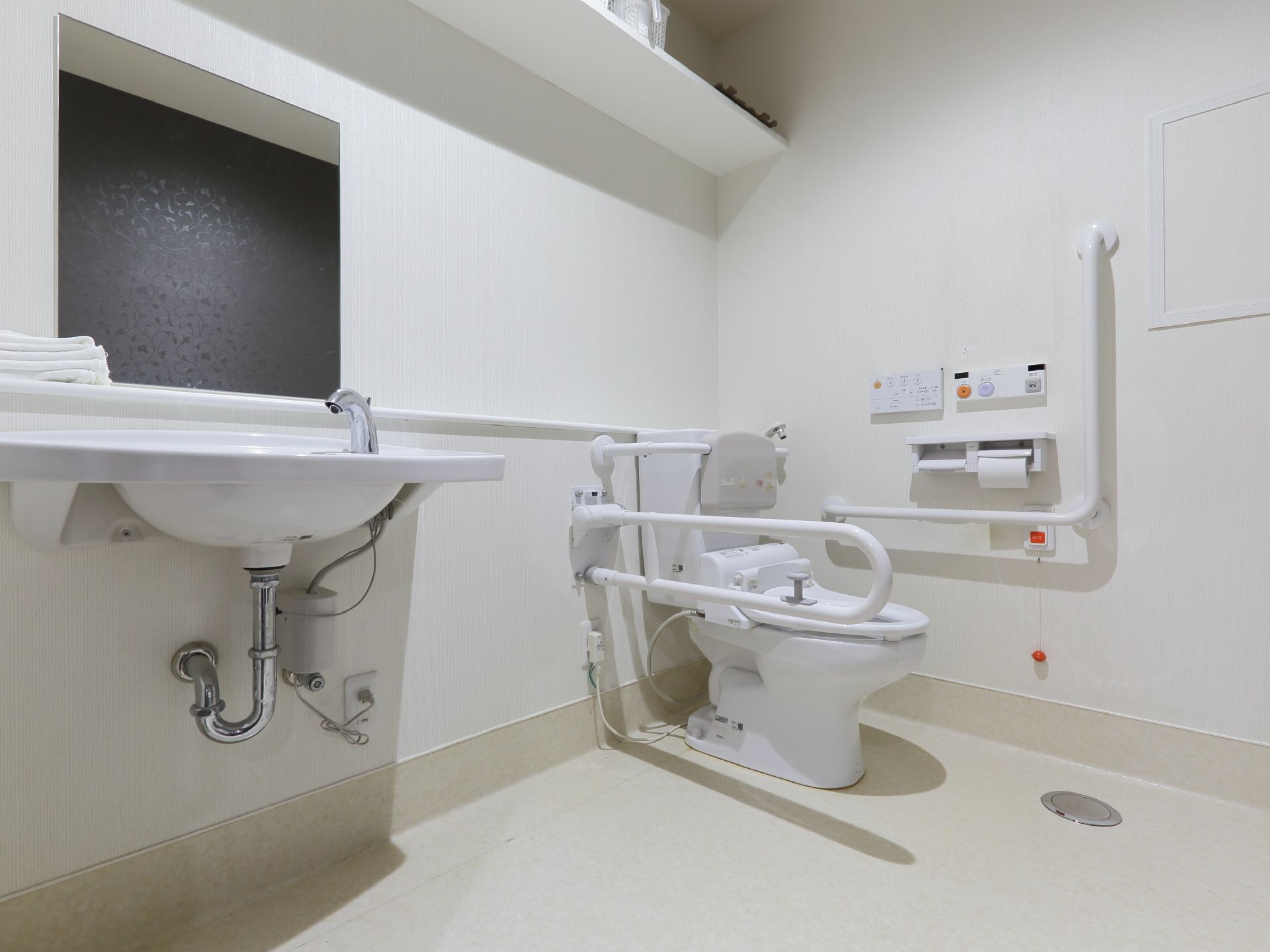 トイレ内は広く、便器脇に可動式の手すりが設置されている。ナースコールや洗面台も備わっている。温水洗浄便座である。