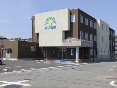建物の前に駐車場が広がっている、三階建ての施設外観