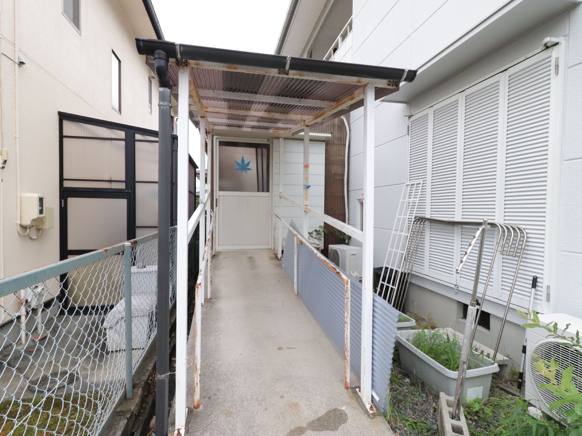 鉄板の屋根が設置され、手すりが両脇に付いている屋外にある細い通路
