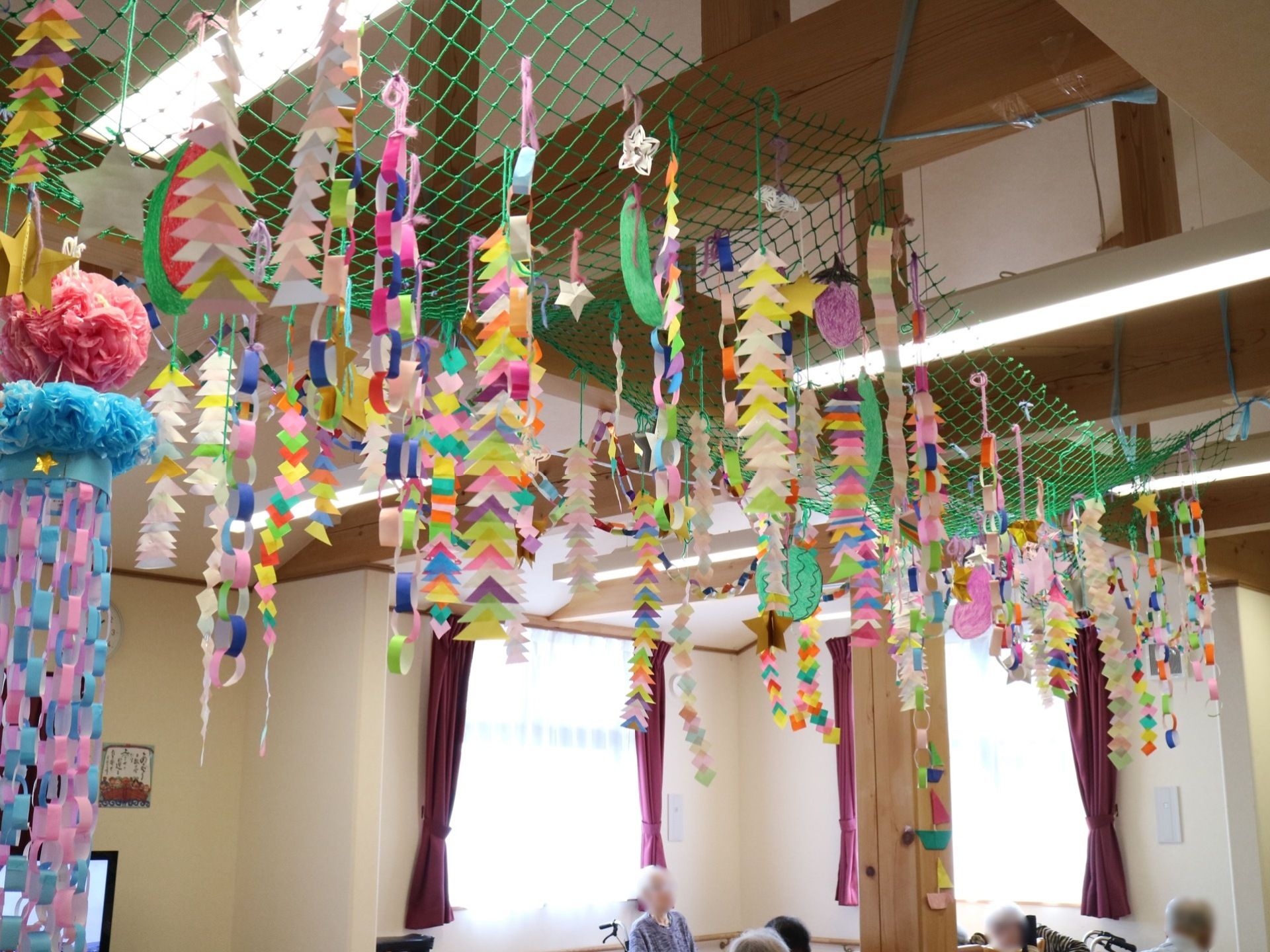 高い天井の大部屋には、梁があり網を活用してさまざまな色のペーパークラフトなどを飾って、華やかさを演出している。
