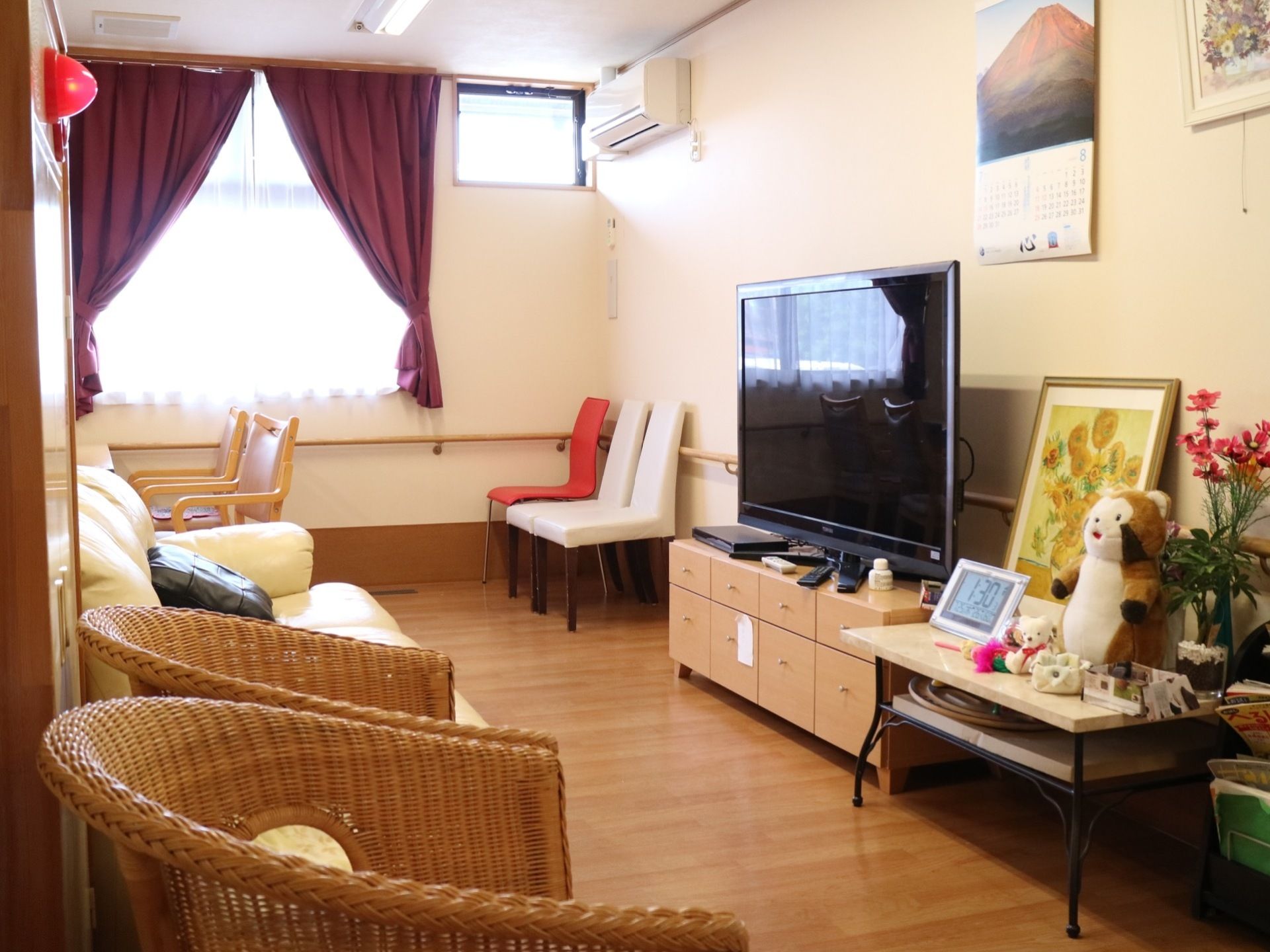中央の横広の棚にフラットテレビを設置している。テレビの前には、ソファーや種類の異なる椅子が複数並べられている。