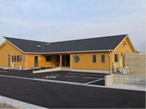 オレンジ色の壁の建物。スロープや駐車場が設けられている。