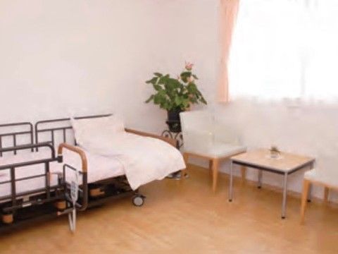 介護用ベッドとテーブルセットが配置された、フローリングの部屋。