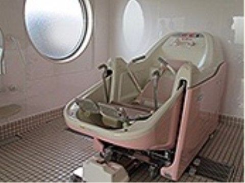 丸い窓のある浴室。介護浴槽が置かれている。