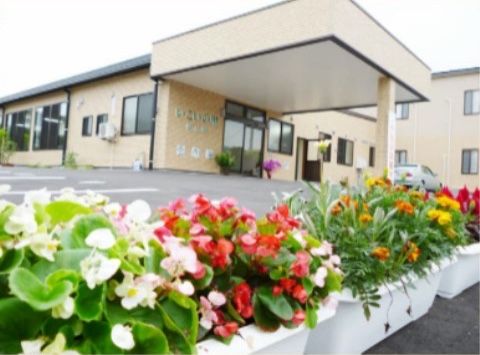 施設の建物の前に、たくさんの花が植えられて置かれている複数のプランター