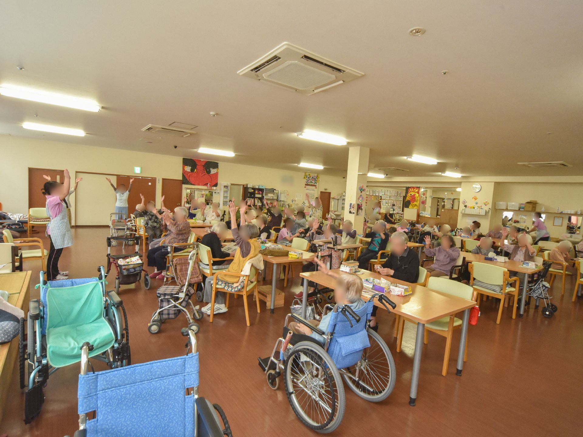 白色と茶系の内装に横面の窓がある。テーブルと椅子が並べられ、天井にはエアコンと照明が設置されている。壁には手作りのレイアウトが施されている。