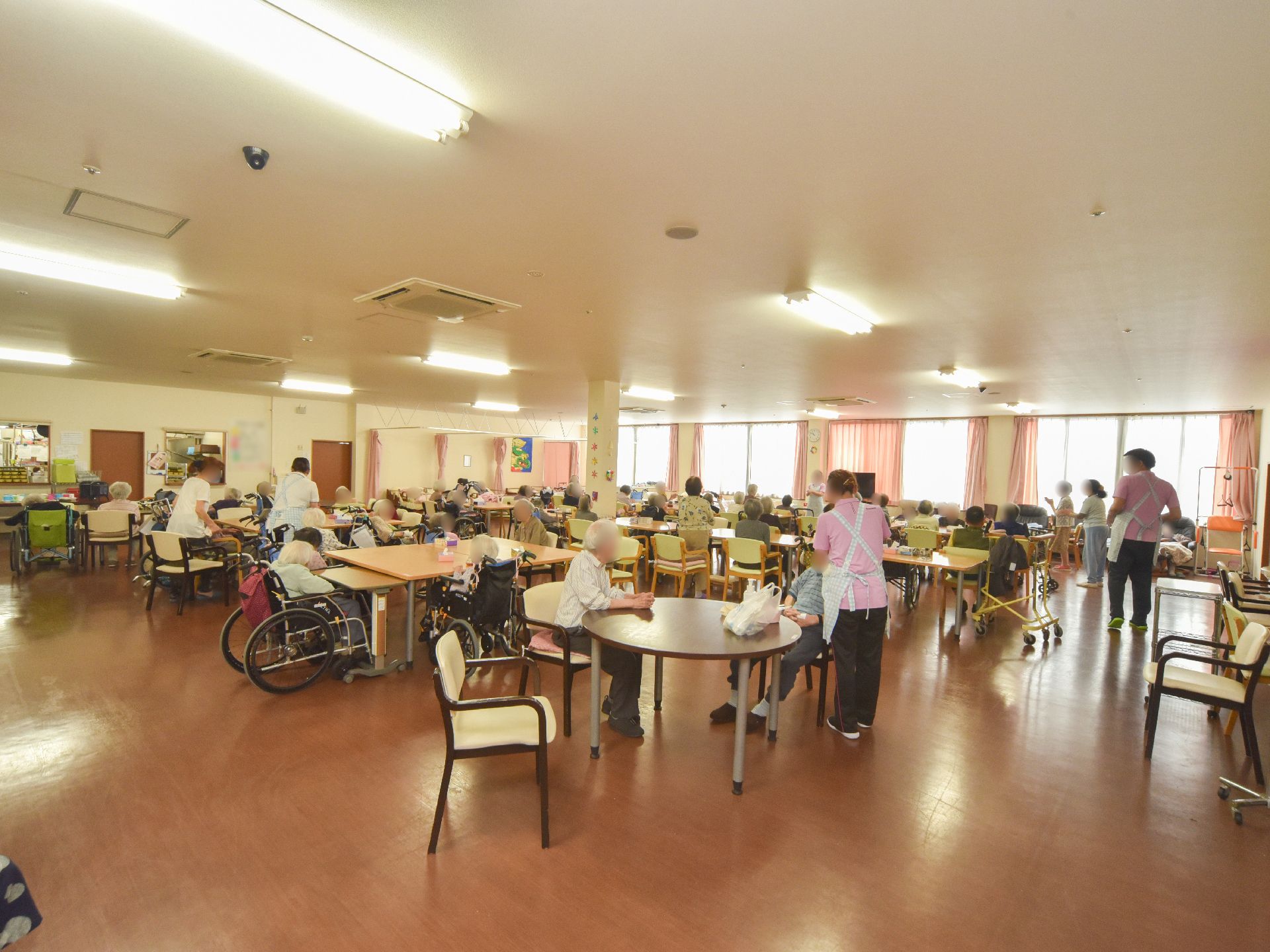 白色の天井と壁に茶色の床。四角テーブルや丸テーブルと椅子が並べてある。横一面は窓になっていて、その前方の真ん中にテレビが置いてある。