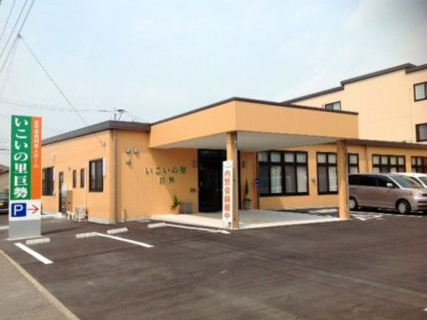 手前に広い駐車スペースを持つ、外観が薄黄色の施設建物