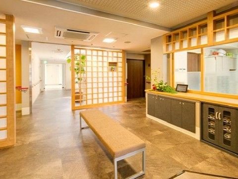 「プレミアムハートライフ千代田」のエントランス。ベンチに座りながら靴を履きやすい体制を整えている。