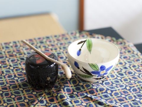 和風の布の上に並べられた、湯飲みと粉末のお茶セット