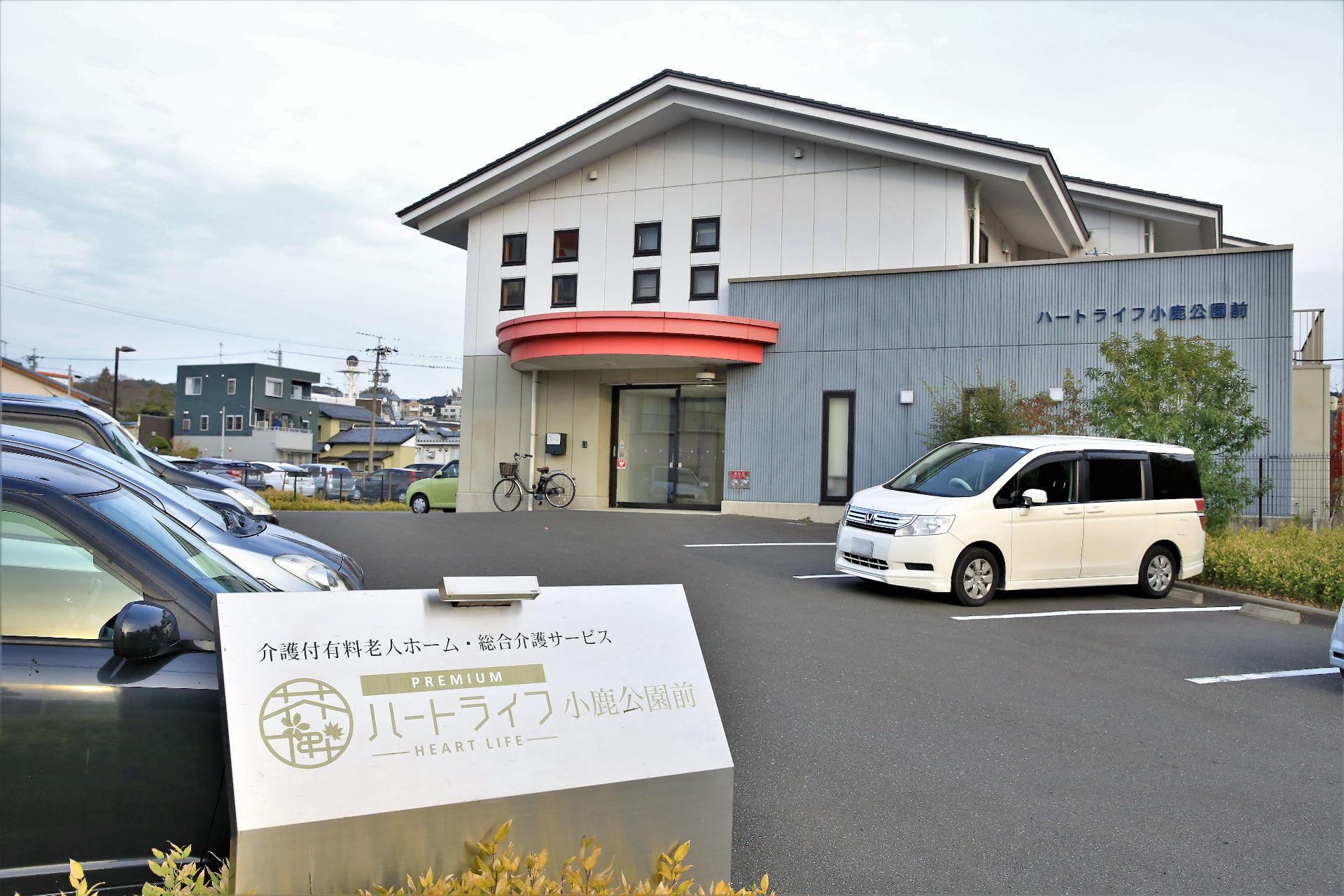 玄関前に赤塗りの雨除けルーフが付いている、三角屋根の施設外観