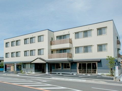 ハートライフ高柳の外観。白を基調とした外壁が清潔感を与える施設外観。大きな駐車場を完備している。