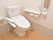 手すりが取り付けてある。トイレットペーパーホルダーが二つ壁に取り付けてある。壁に、緊急時呼び出しブザーが取り付けてある。