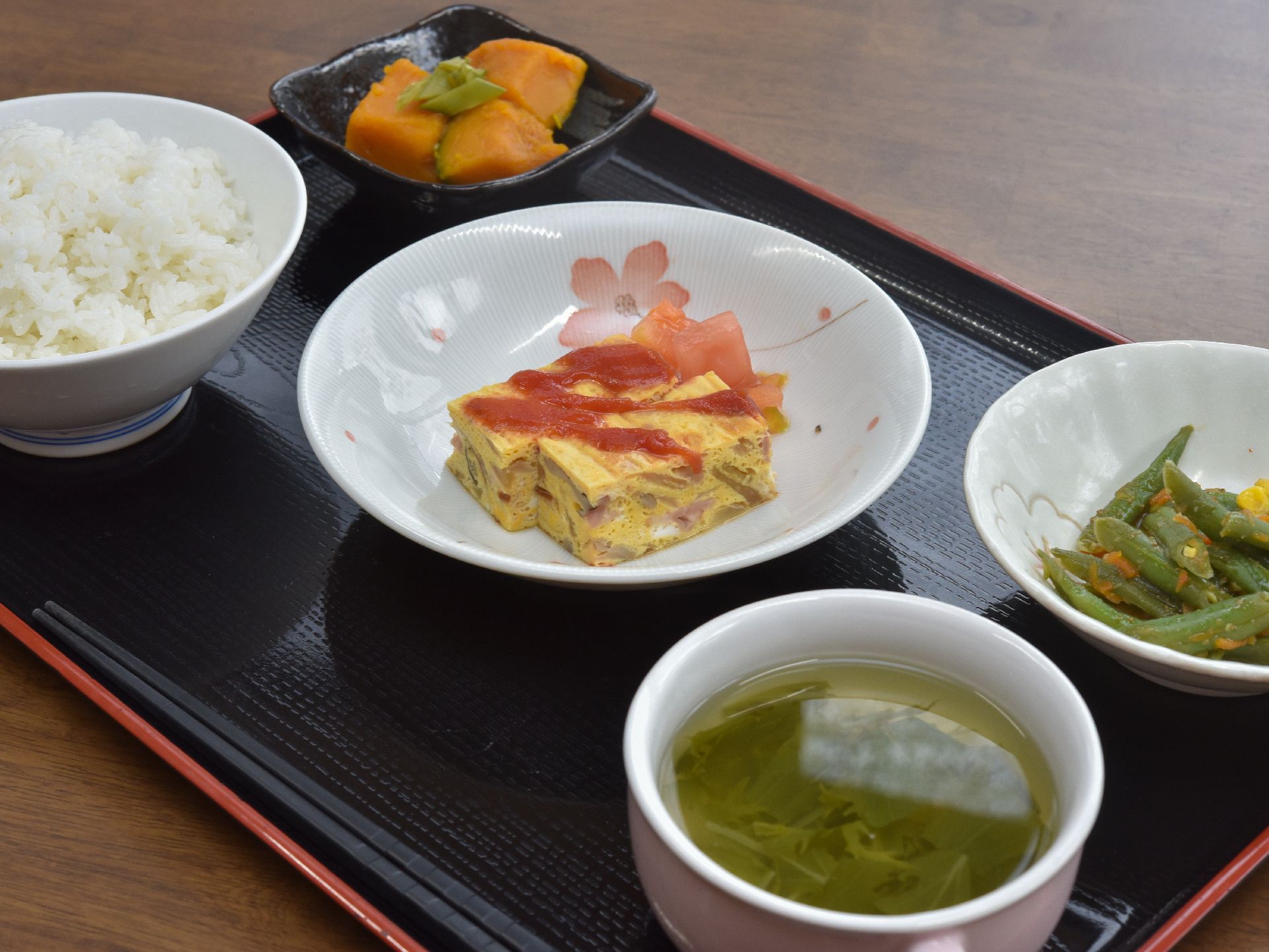食事は一人一人お盆の上にのせて配膳される。主食の他にも小皿に入ったおかずが何品かあり、旬の野菜を使っていて栄養バランスもよい。