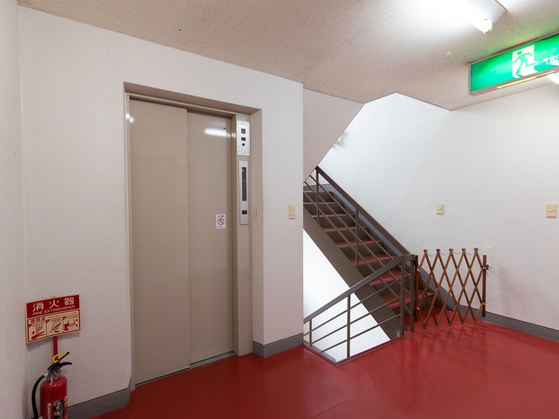 エレベーター前は広くなっている。直ぐ隣には、非常口を兼ねた階段が設置されている。階段の前には柵が設けられている。