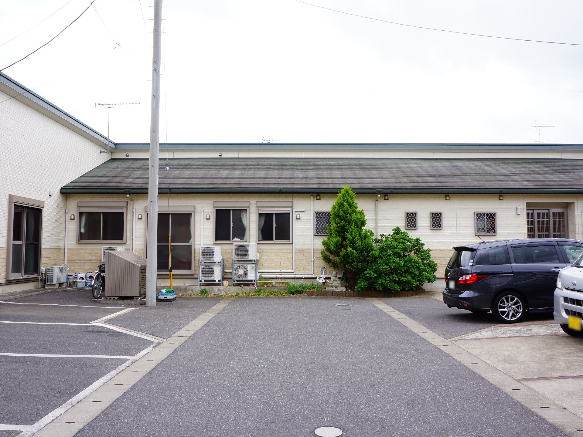 駐車場の完備されている施設には、複数台車が止められるようになっている。外観は落ち着いた雰囲気のオフホワイトのいろである。