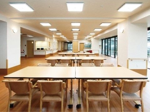 揃いのテーブルセットが規則正しく並べられている、広々としたダイニング