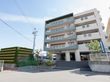 高台にある施設で、５階建てである。１階に駐車場があり、入口に施設名が表示されている。青いのぼりが立っている。