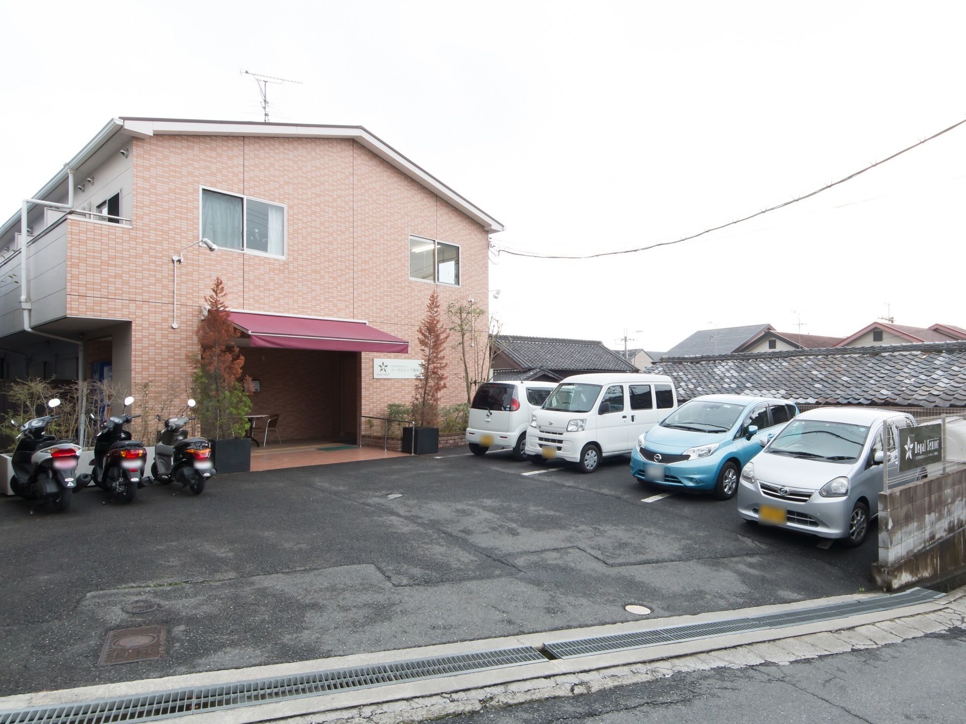 施設建物は坂のある場所に建てられている。高台を造成した敷地はアスファルト舗装され、駐車場が設けられている。