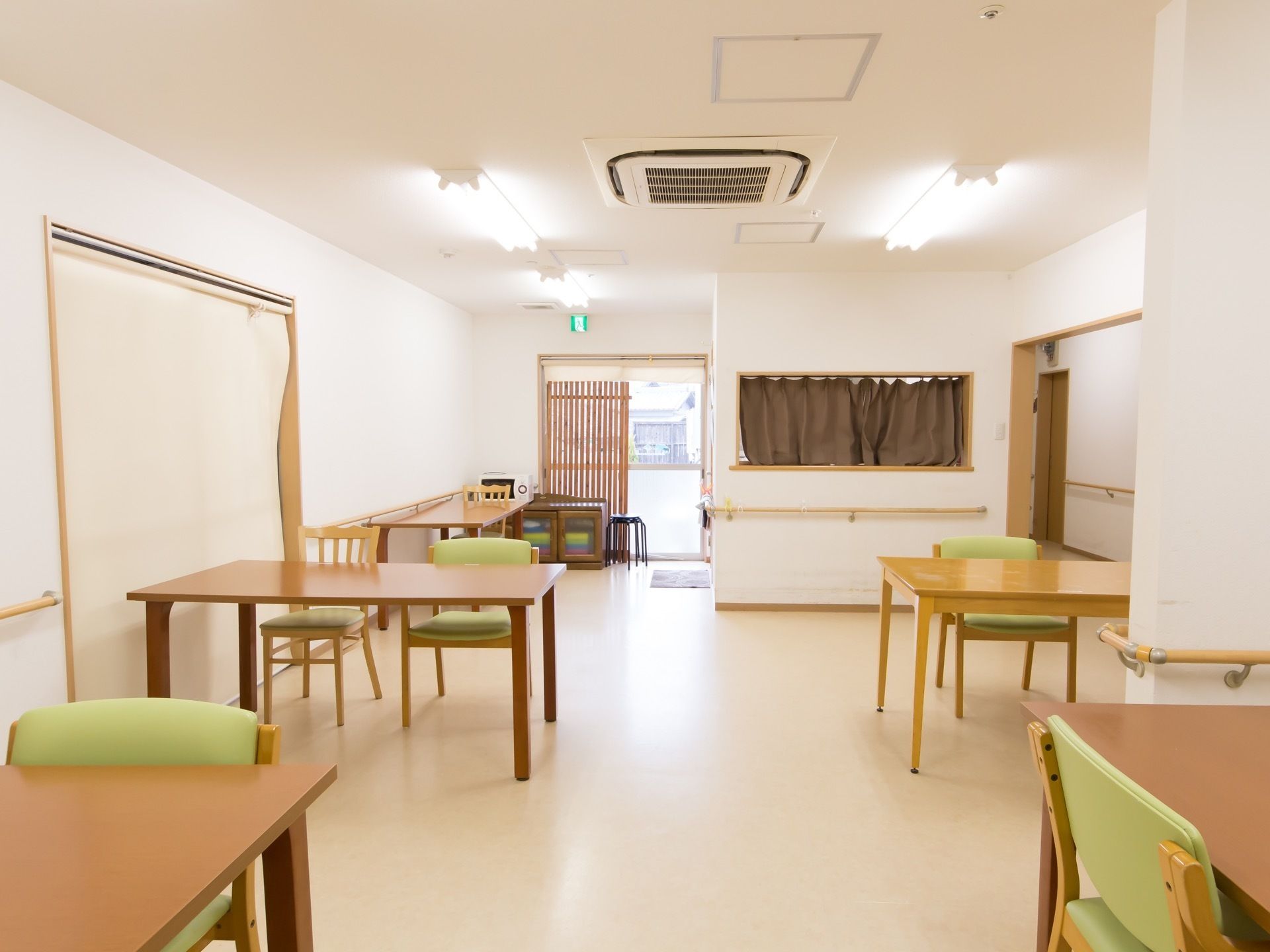 明るくて広い部屋である。ダイニングテーブルと椅子がセットされ、数組置かれている。天井には大きなエアコンが設置されている。
