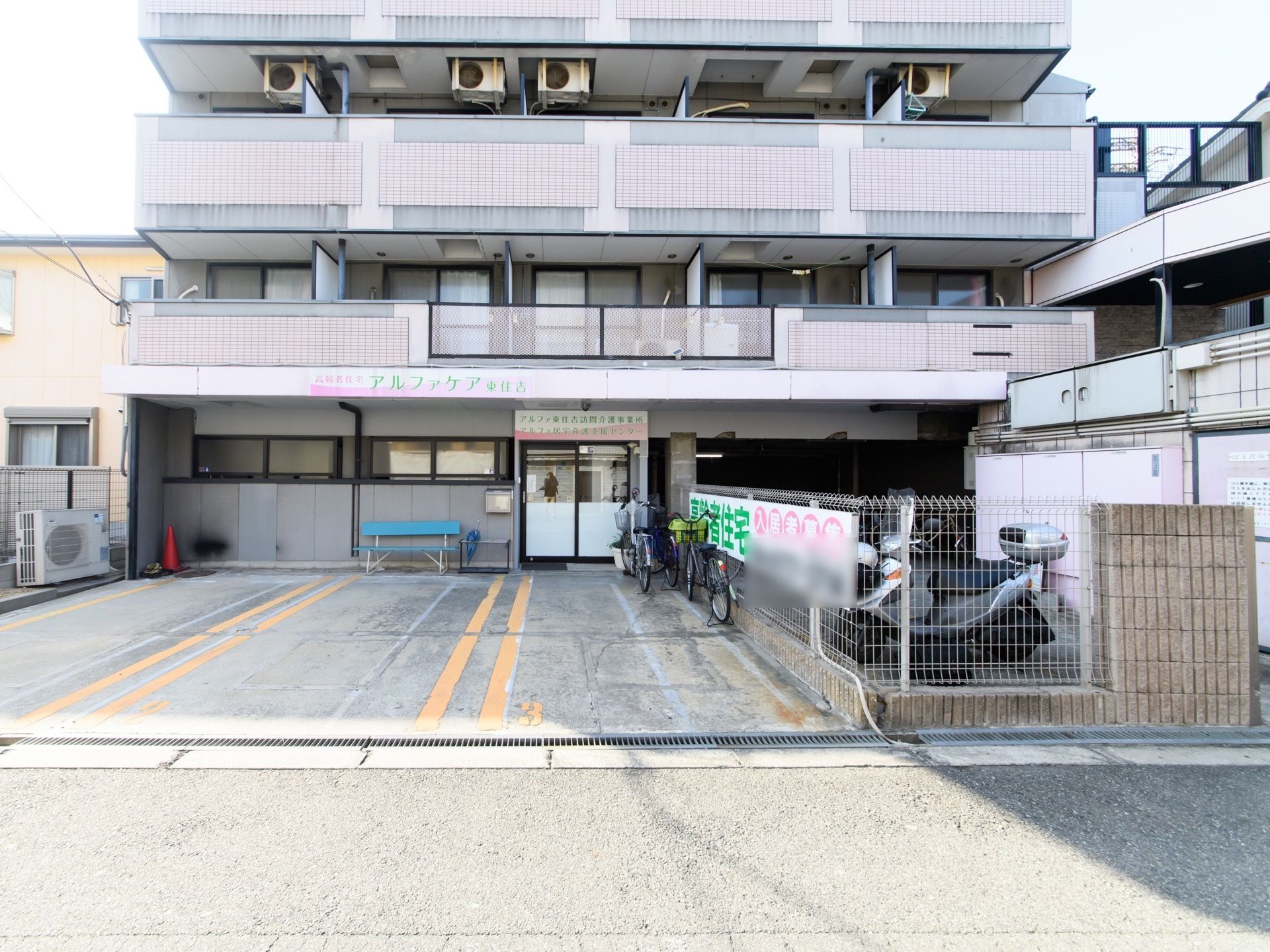 大型車も駐車可能なスペースが３カ所あり、駐輪場も完備している。外にベンチがある。道路から各居室の広いベランダが見える。