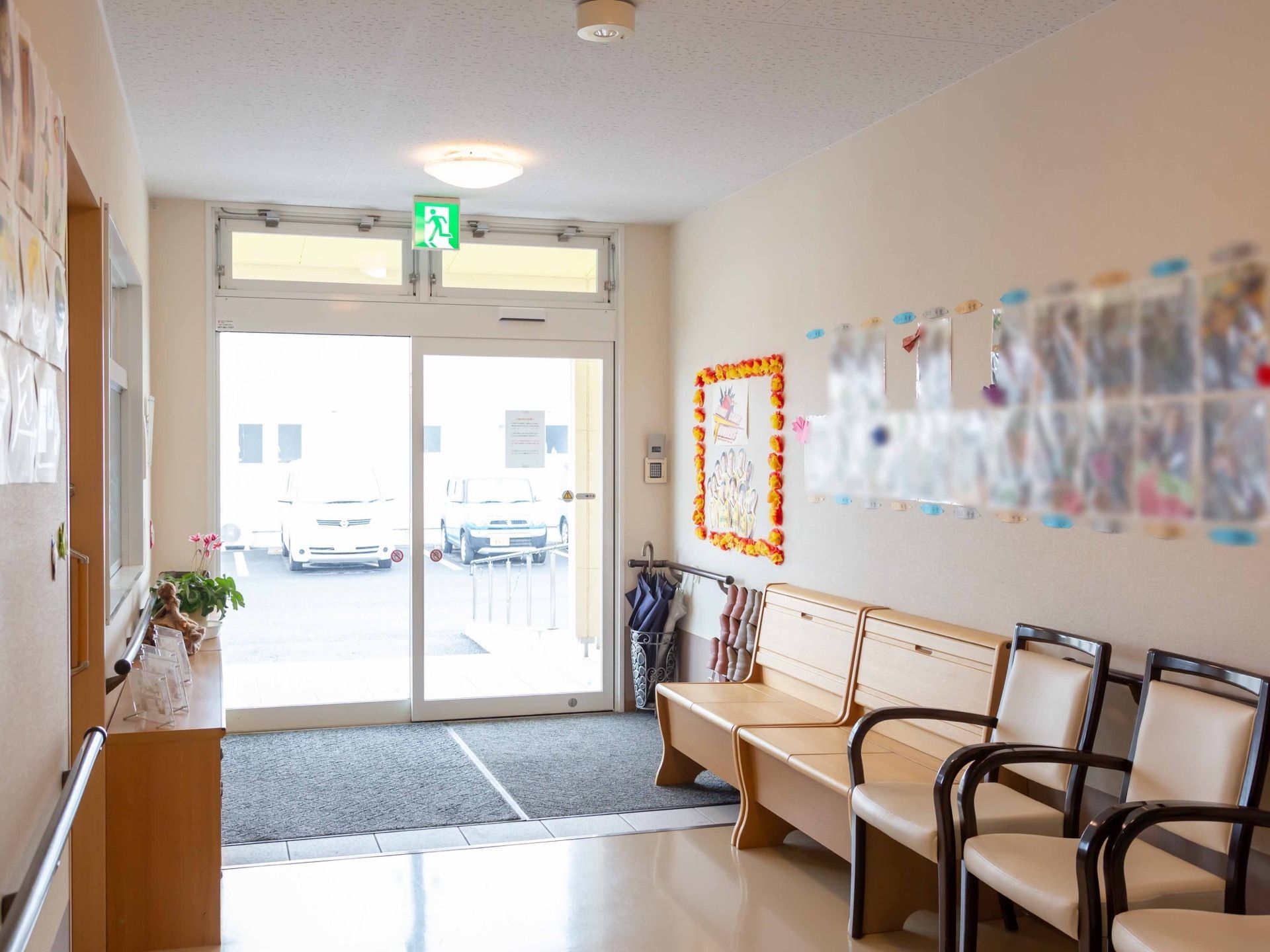 玄関から左側の壁際に一人掛けの椅子を並べている。壁に飾られた飾りや掲示物は、アットホームな雰囲気を醸し出している。