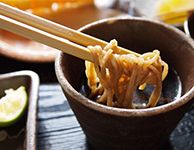 そばを箸でめんつゆにつける様子