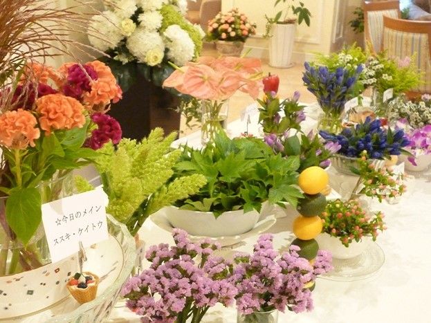 テーブル上の花器に飾られている、色鮮やかな花々や植物