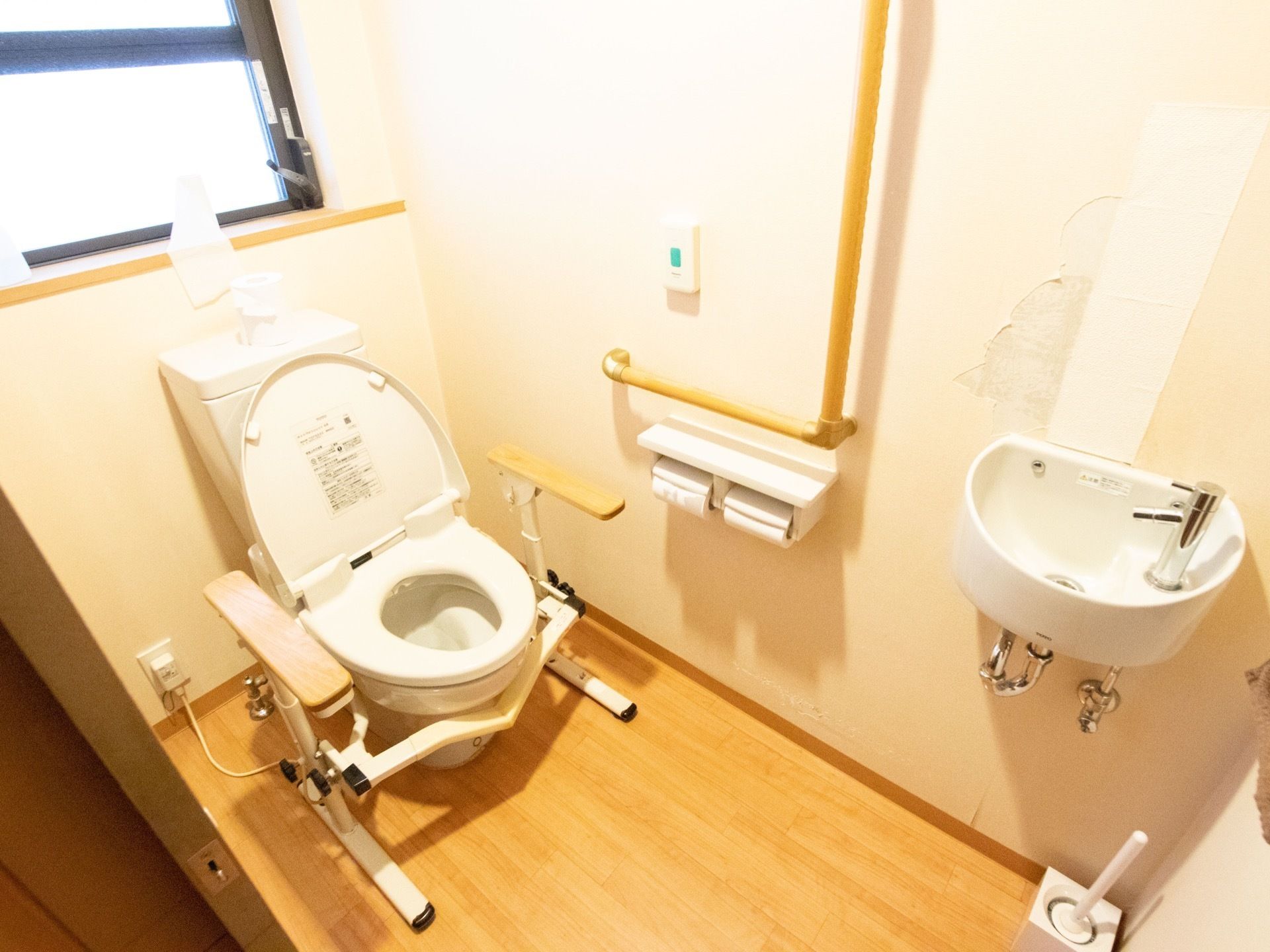 便器の両脇だけでなく、壁にも手すりがあるので安心してご利用いただける。窓があるので明るく、清掃も行き届き衛生的である。