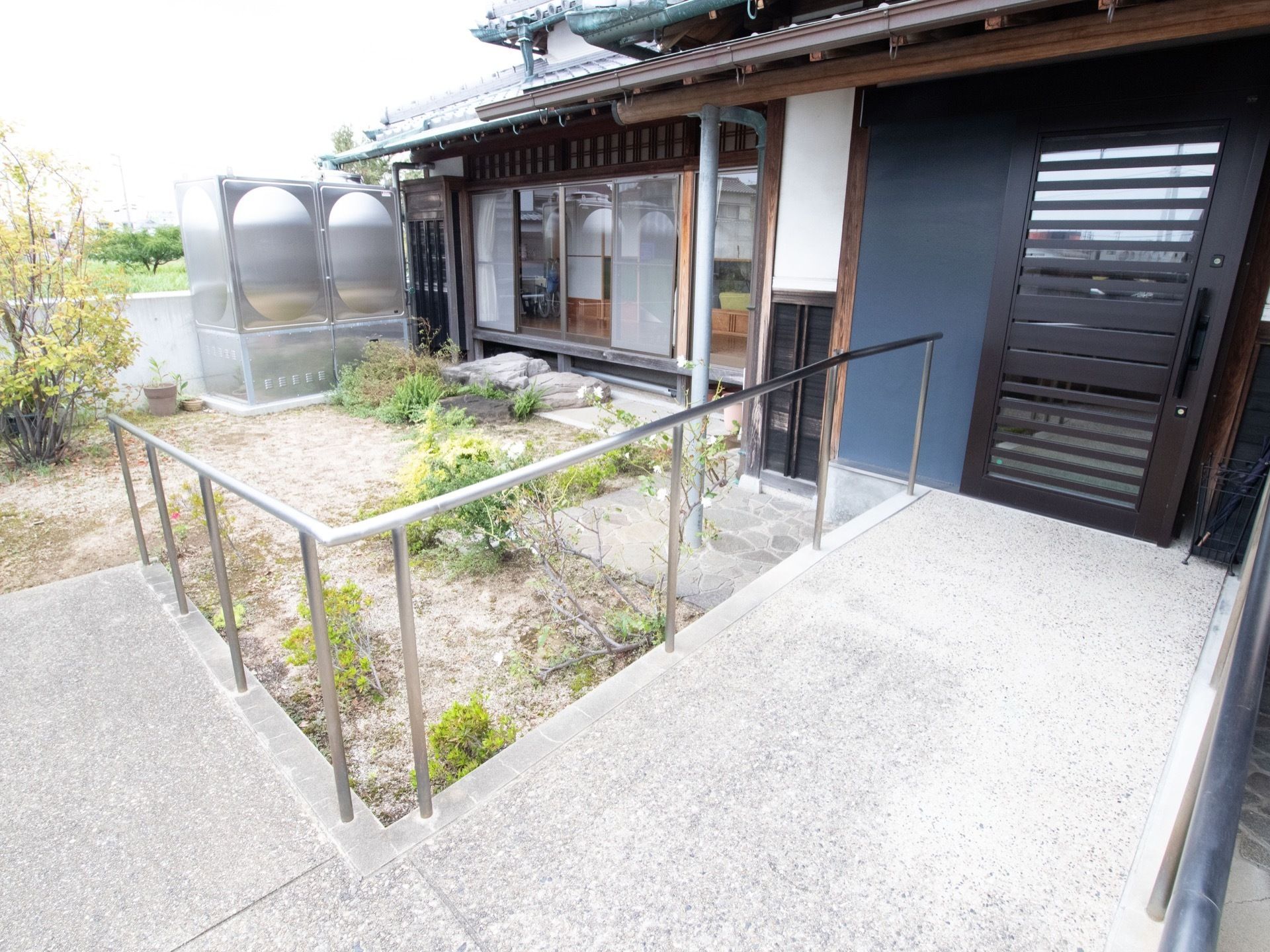 庭を通って玄関にたどり着くようになっている。スロープになっており、手すりがついている。扉は横開きを採用している。