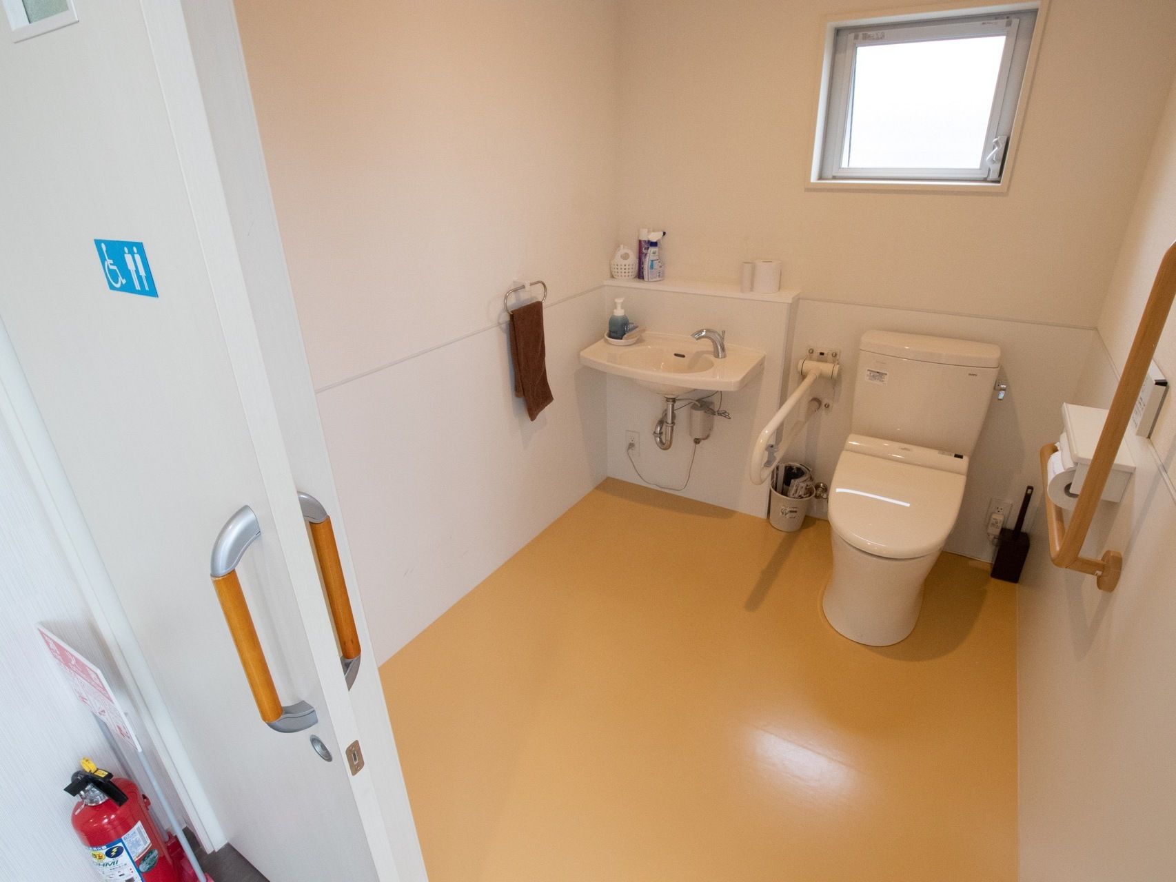 トイレは温水洗浄便座を設置しており、折り畳み式の手すりが便座の横に取りつけられている。壁にタオル掛けがある。