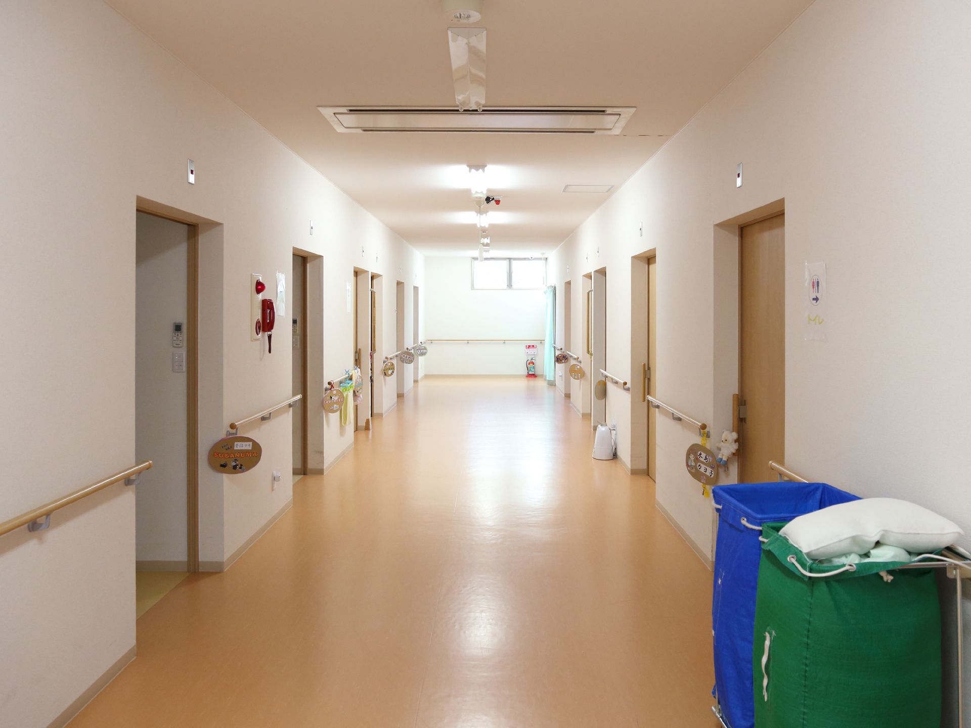 廊下は幅が十分にとられている。段差はなく、両側に手すりを設置している。部屋の入り口に看板が掲示されている。
