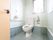 床にタイルが使われているトイレである。片方の壁にはL字型の手すりが備わっており、反対側には可動式の手すりが設置されている。