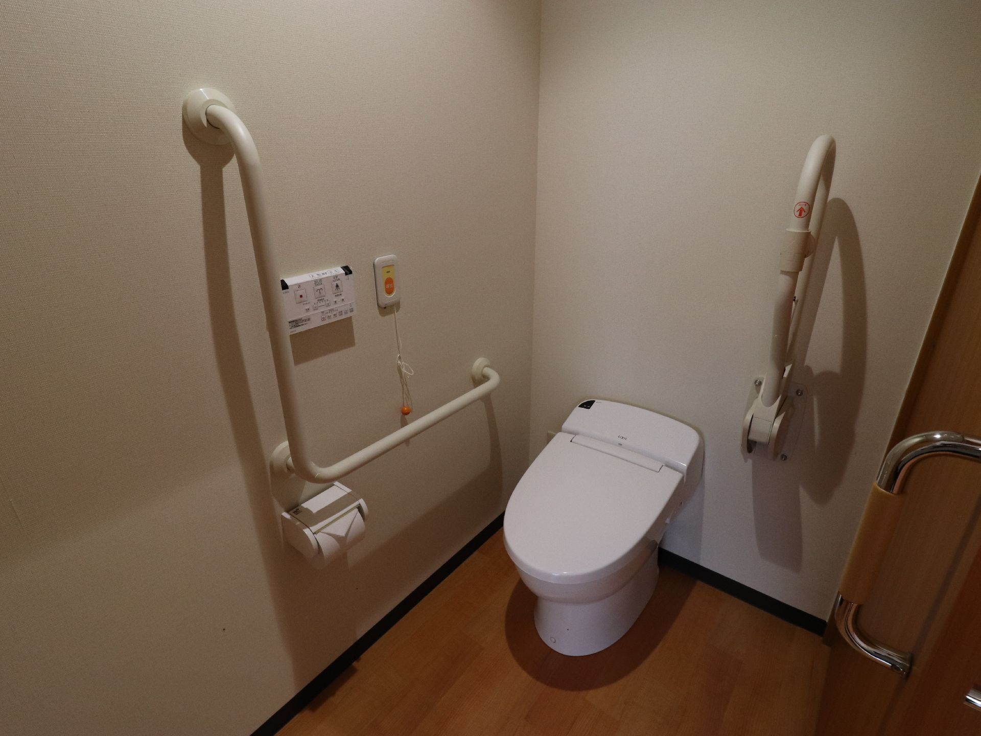 広く、手摺が設置されたトイレは車椅子からの移動も容易にできる。壁には温水便座のリモコン、ナースコールがある。