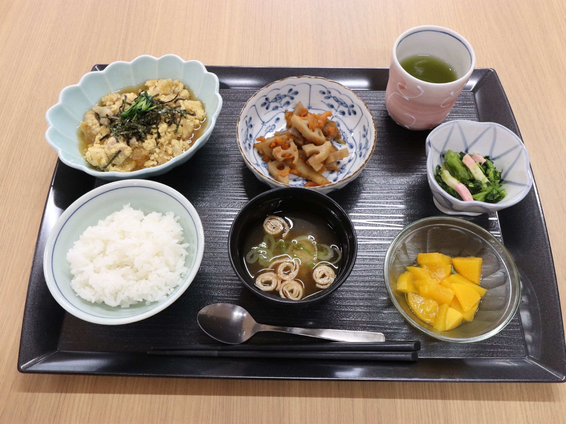 ご飯、汁物、メイン、小鉢2品、フルーツ、お茶の食事。彩り良く盛り付けられ、器も柄があるものを使用している。