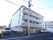 施設は総4階建てである。2.3.4階にベランダがある。1階施設前は縦列駐車ができるスペースがある。出入り口ドアはオレンジ色である。