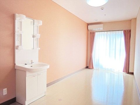 奥に明るい日が差し込む窓があり、白い洗面台が設置された居室