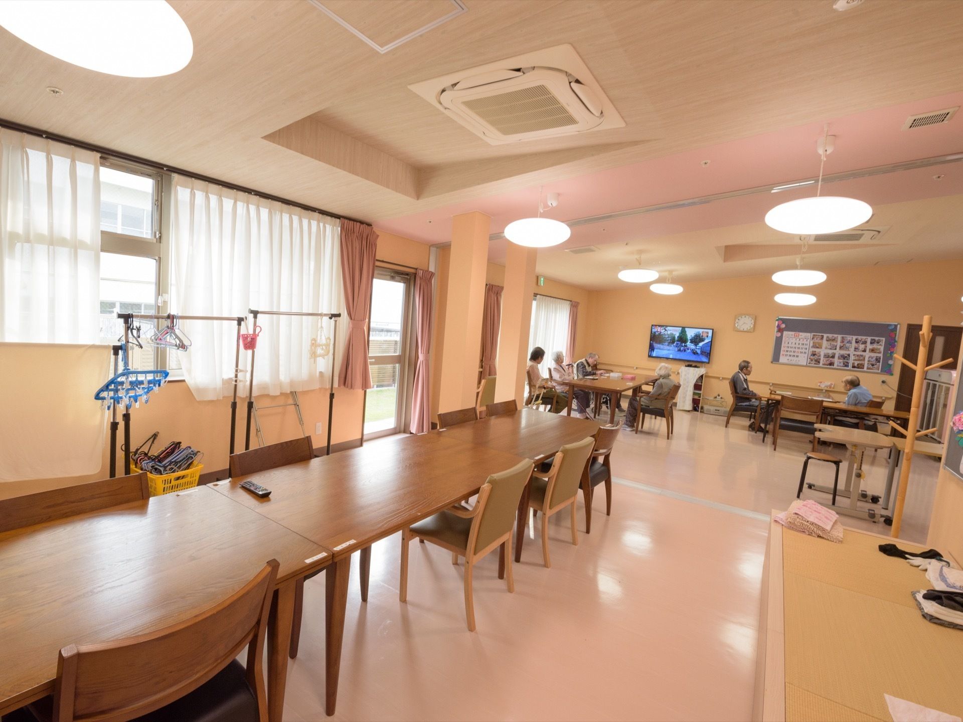 空調を完備した共有スペース。大型テレビが完備されている。入居者様がテレビ鑑賞や趣味等をして時間を過ごしている。