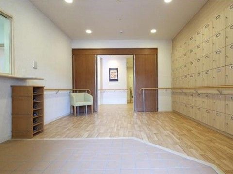 広々としたエントランス。左側には受付カウンター、右側には壁面を利用して下駄箱が設置されている。フラットな床が奥の廊下まで続いている。