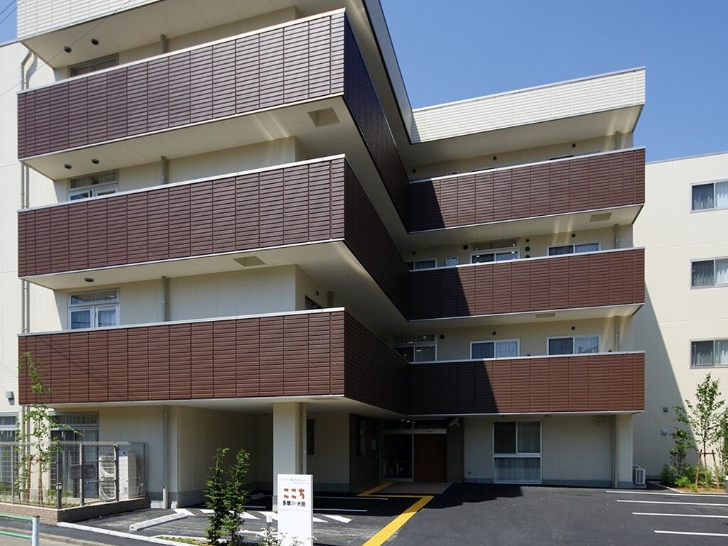 Ｌ字型になっている４階建ての建物で、白い外壁に茶色のベランダが特徴的である。入り口そばに駐車スペースが用意されている。