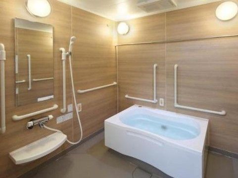 白色の浴槽が備わる浴室である。室内は明るい茶色の木目を基調としている。手すりや緊急時呼び出しブザーが設けられている。