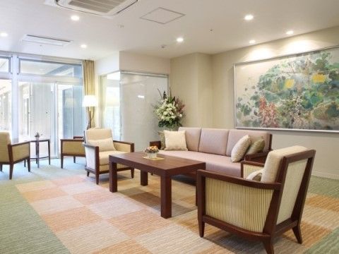 絵画や花で装飾されたエントランス。フロアマットの上にソファーセットが据えられており、広く開放的な窓辺にもテーブルセットが用意されている。
