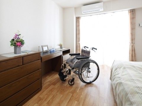 大きな窓から自然光が差し込む開放的な居室。ゆとりのある広さで、車椅子をご利用の方も過ごしやすい。エアコンも設置されている。