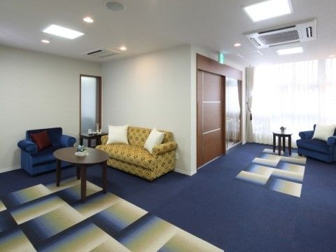 深い青のカーペットが敷かれ、ソファとテーブルが置かれたエントランス。大きな窓から光が入り、明るくくつろげる空間である。