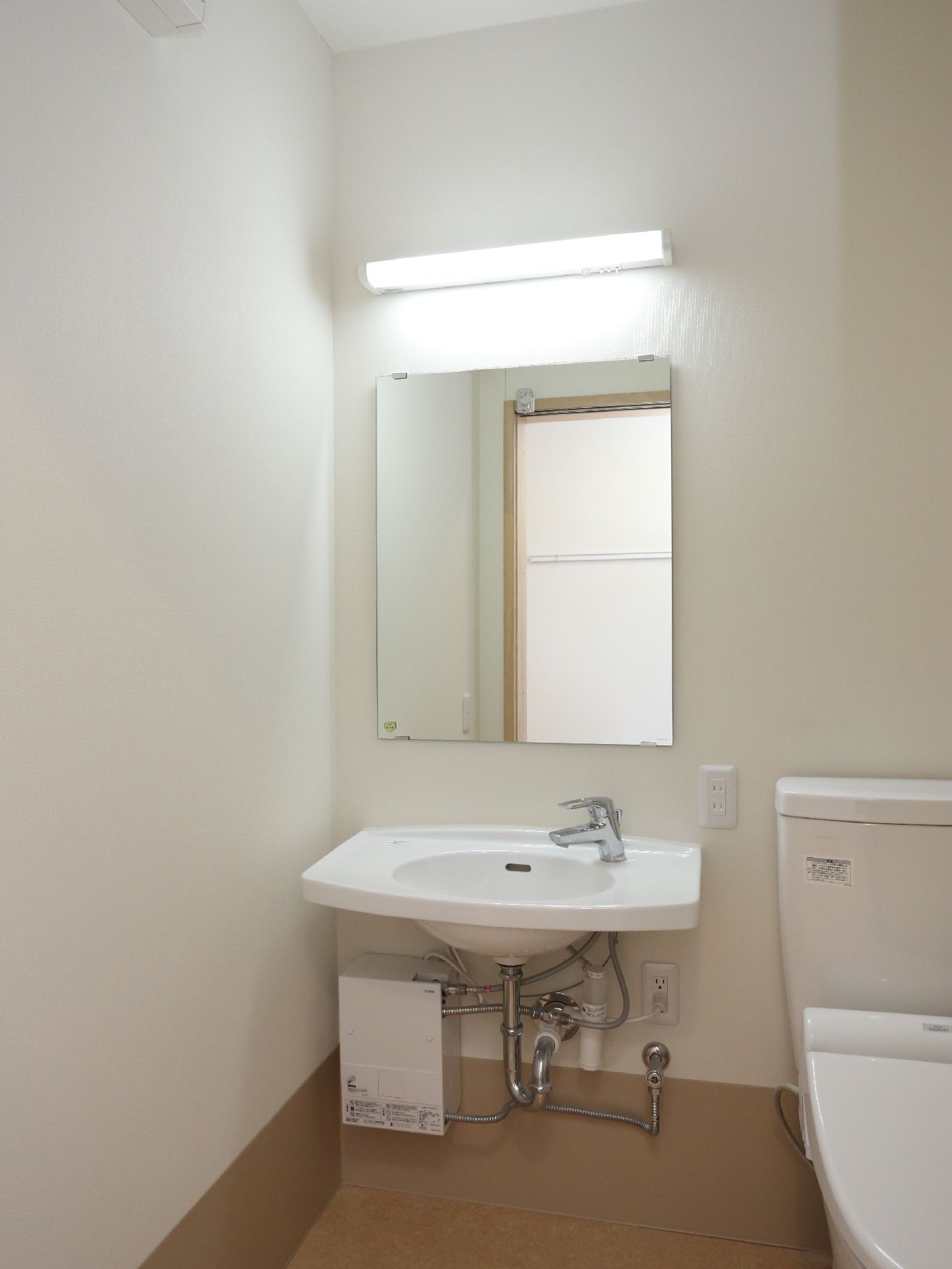 大きな鏡が付いている洗面台は、車いすに乗ったまま使用できるよう、洗面台の下に棚や物が設置さていない。