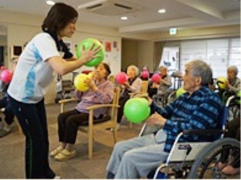 色とりどりのゴムボールを手に、運動をする大勢の入居者様